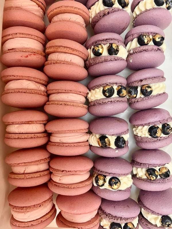 Ряди малинових та чорничних макаронс з кремом і свіжими ягодами зверху