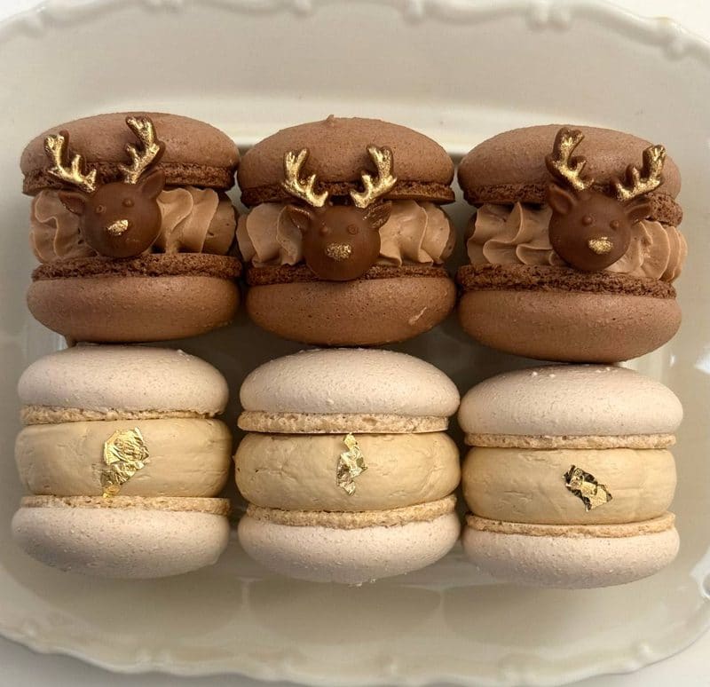 Різдвяні макаронс у формі оленів з шоколаду та золотими рогами поряд із ванільними макаруні