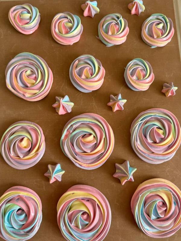 Райдужні меренгові троянди пастельних кольорів та маленькі зірочки на деку з випічкою